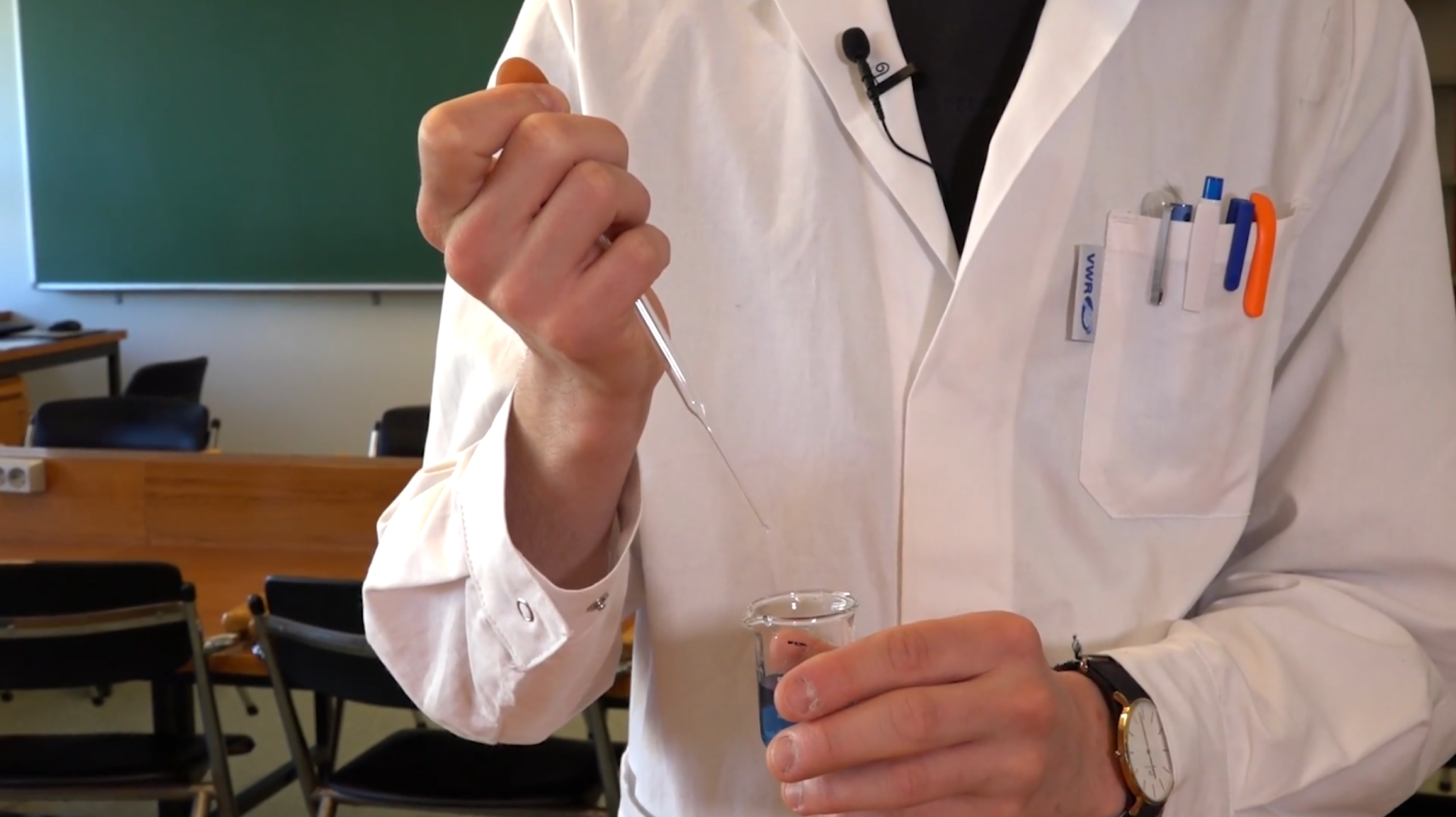 en student bruker en pasteurpipette for å overføre væske i et begerglass